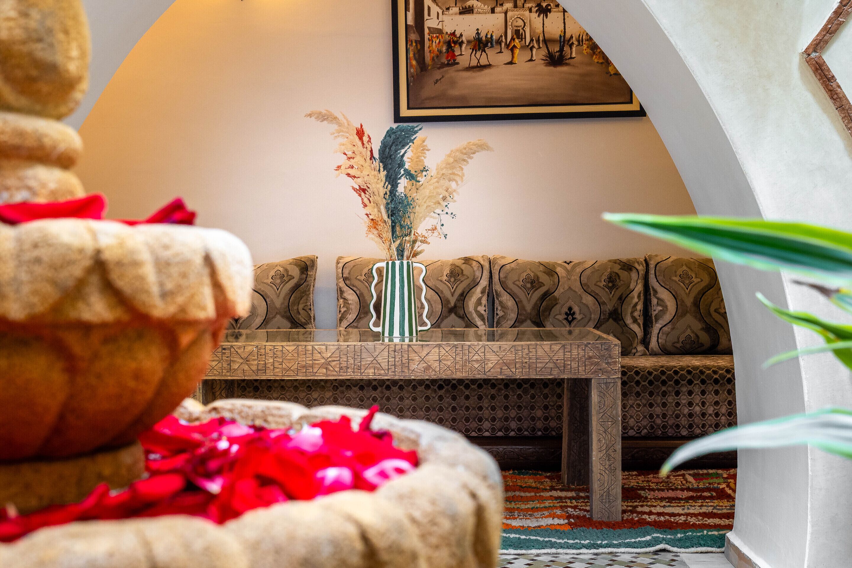 A traditional room with a patterned sofa, a decorative vase, and a framed picture on the wall.