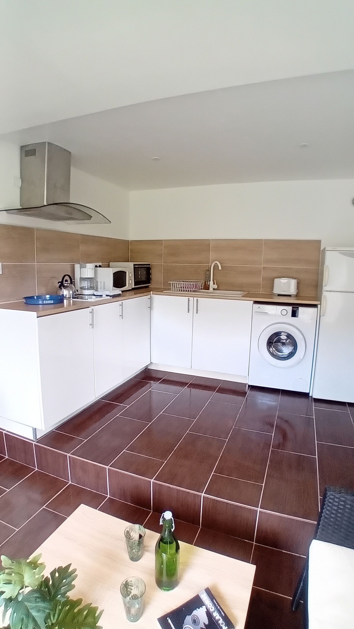 A compact kitchen with white cabinets, a built-in washing machine, and a microwave.