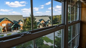 A view from inside a building looking out at a row of wooden houses with green roofs and a clear blue sky.