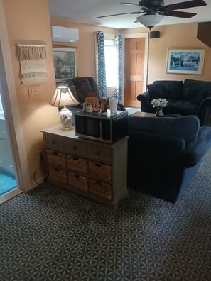 A living room with a sofa, a coffee table, a lamp, a TV, and a ceiling fan.