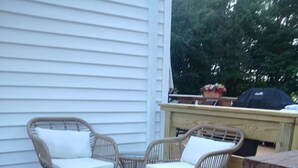A deck with wicker chairs and a planter.