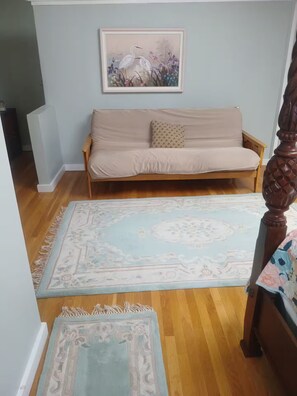 A room with a sofa, a framed painting, and two rugs.
