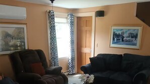 A living room with two sofas, a coffee table, and a door leading to another room.