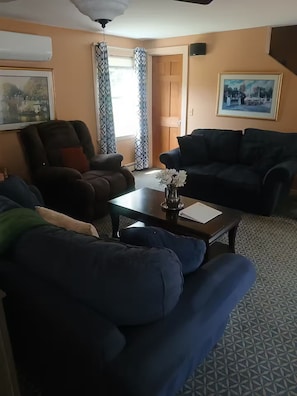 En stue med to sofaer, et sofabord og en dør til et andet rum.