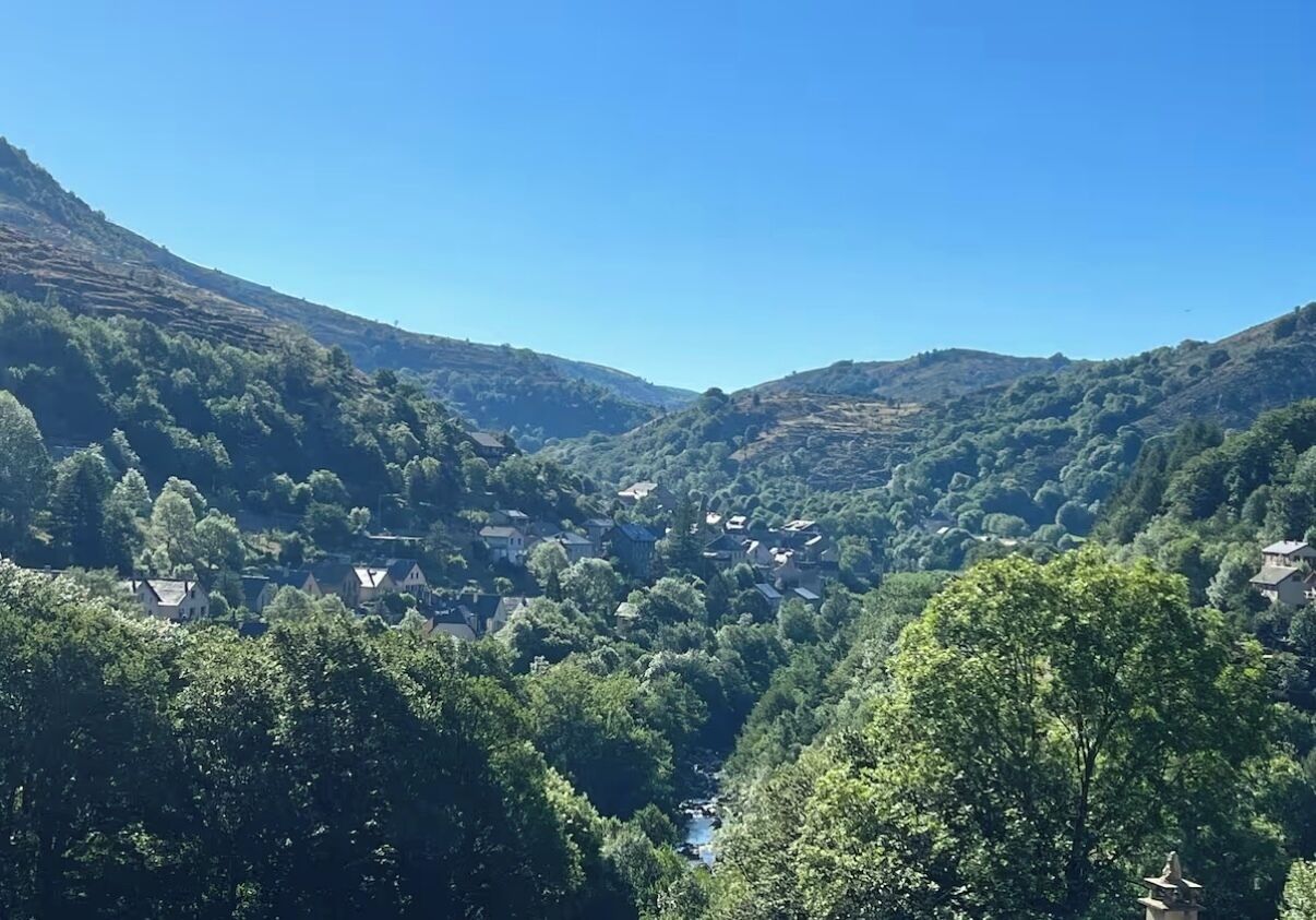 A valley with houses surrounded by dense greenery and hills.