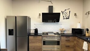 Une cuisine moderne équipée d’appareils électroménagers en acier inoxydable, d’un four à micro-ondes et d’un téléviseur fixé au mur.