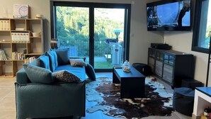 Un salon avec un canapé, une table basse, un téléviseur et une bibliothèque.