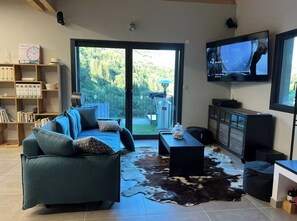 Ein Wohnzimmer mit Sofa, Couchtisch, Fernseher und Bücherregal.