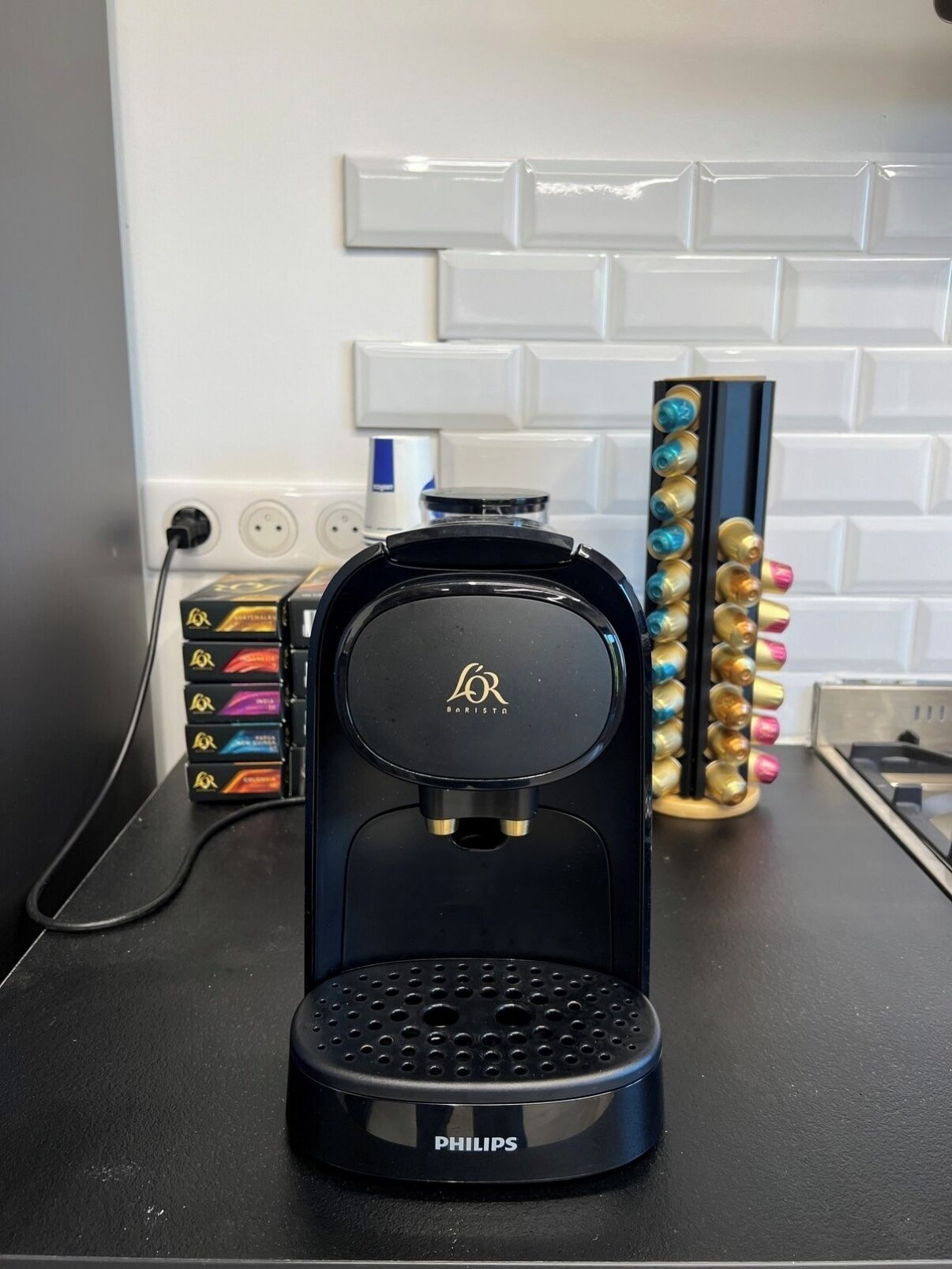 A coffee maker on a kitchen counter with a white tiled backsplash.