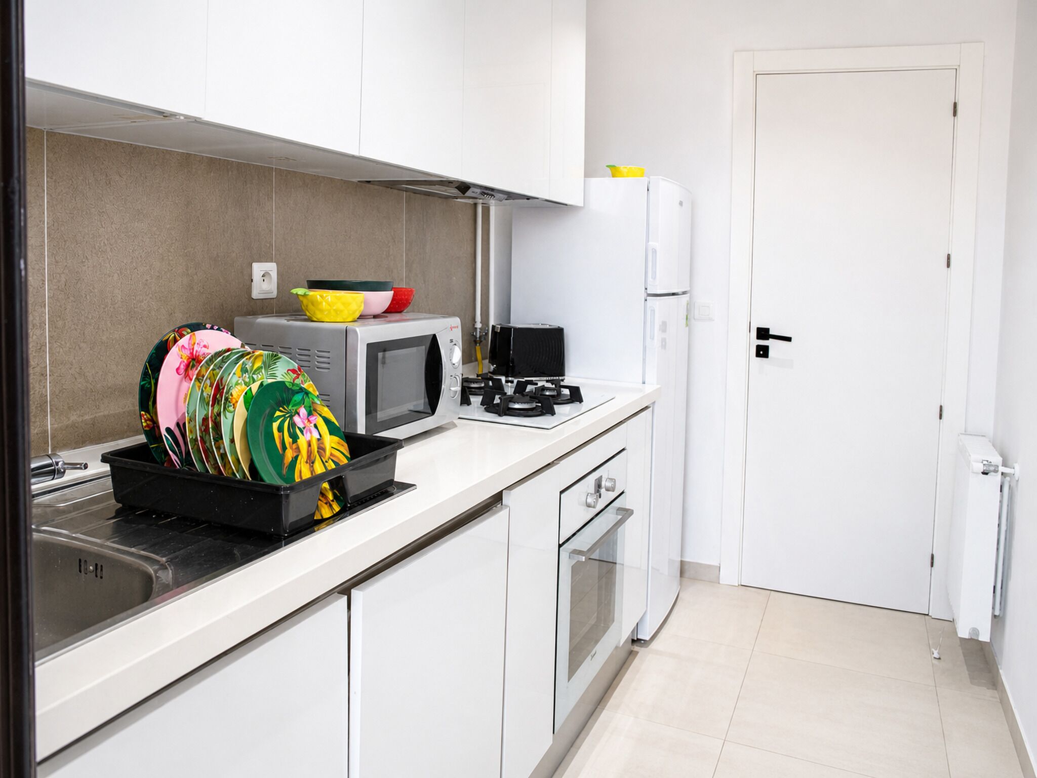 Uma cozinha moderna com armários brancos, micro-ondas, fogão e geladeira.