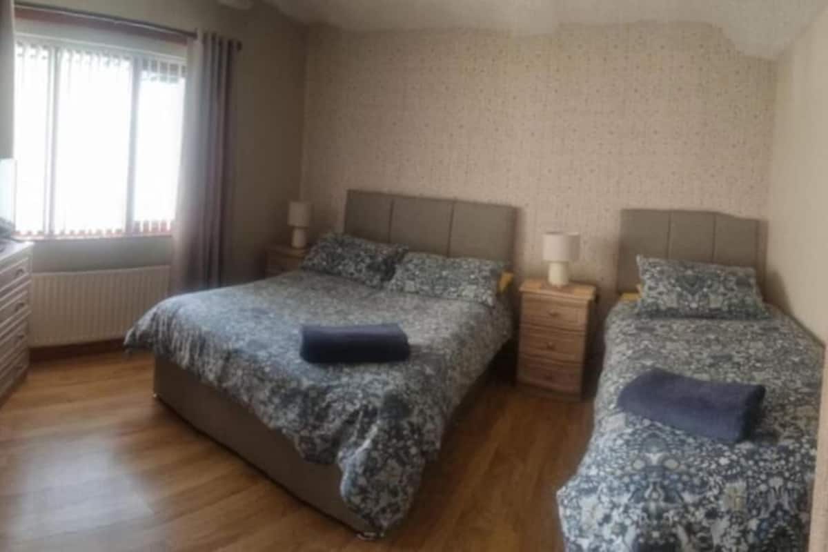 Un dormitorio con dos camas, un aparador, un radiador y una ventana con cortinas.