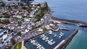 An aerial view of a coastal town with a marina, residential area, and a rocky breakwater. - Church View  (Ballycastle)