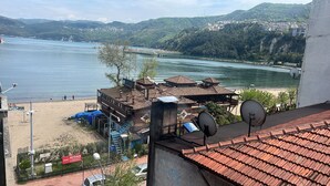 A coastal building with a view of the sea, a beach, and hills in the background. - Sevimli suit konaklama (Amasra)