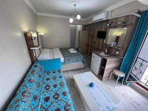 Une chambre d’hôtel avec deux lits, une petite kitchenette, un bureau, une chaise, un miroir et un luminaire au plafond.