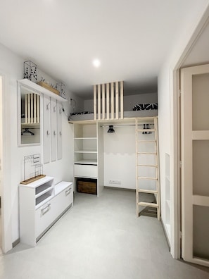 Ein begehbarer Kleiderschrank mit integriertem Schreibtisch, Regalen und einer Leiter.