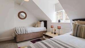Une chambre avec deux lits, une table de chevet, une lampe, un miroir et une vue sur l’extérieur.
