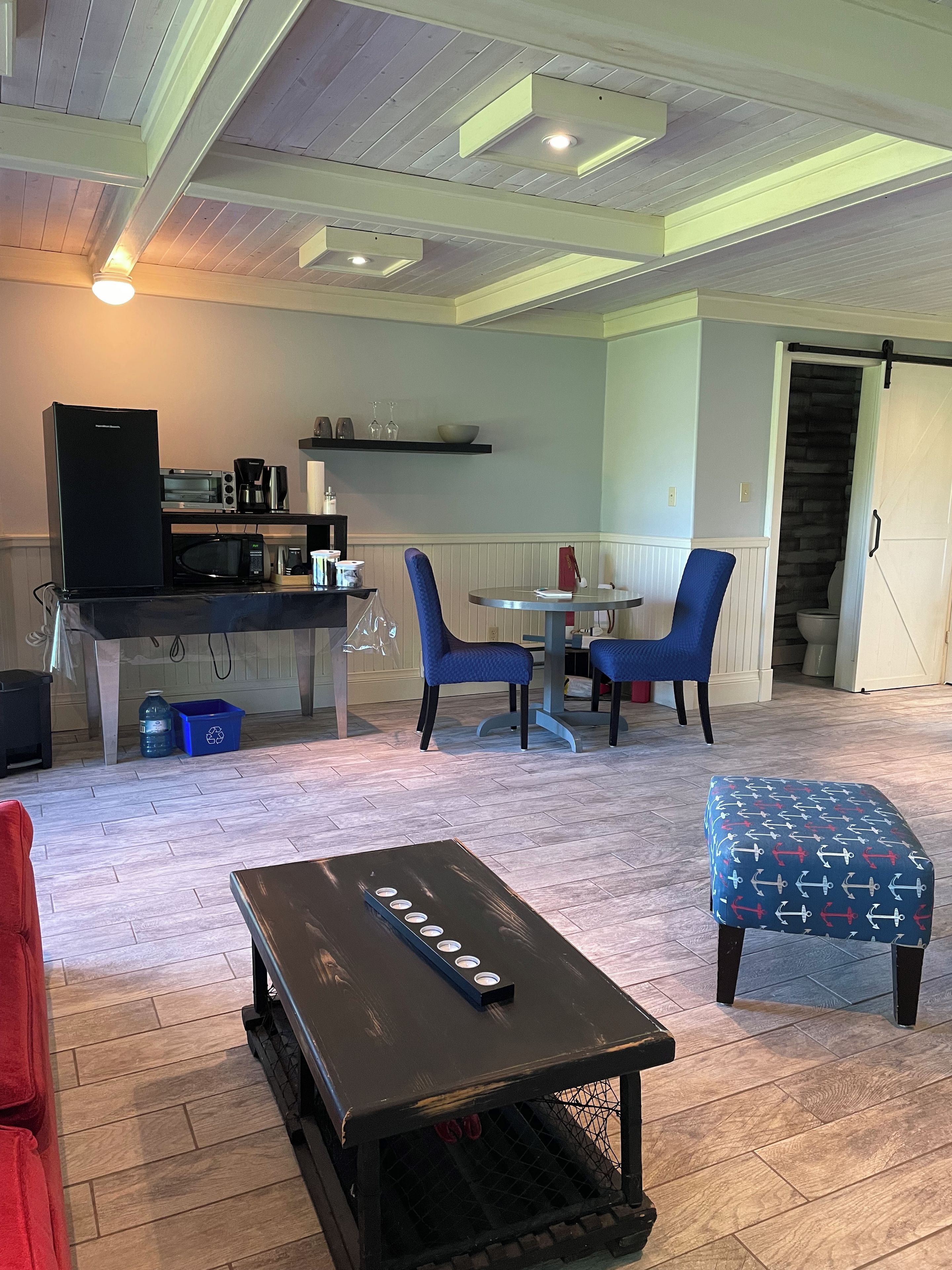 Une cuisine moderne équipée d’un four à micro-ondes, d’une machine à café et d’un grille-pain. On y trouve également un coin repas avec des chaises bleues et une petite table.