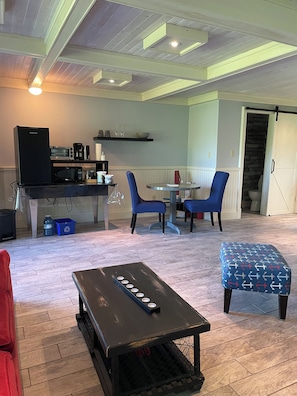 A modern kitchen with a built-in microwave, coffee maker, and toaster. There is a dining area with blue chairs and a small table.
