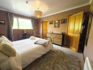 Ein Schlafzimmer mit Bett, Schminktisch, Schreibtisch und Kleiderschrank.