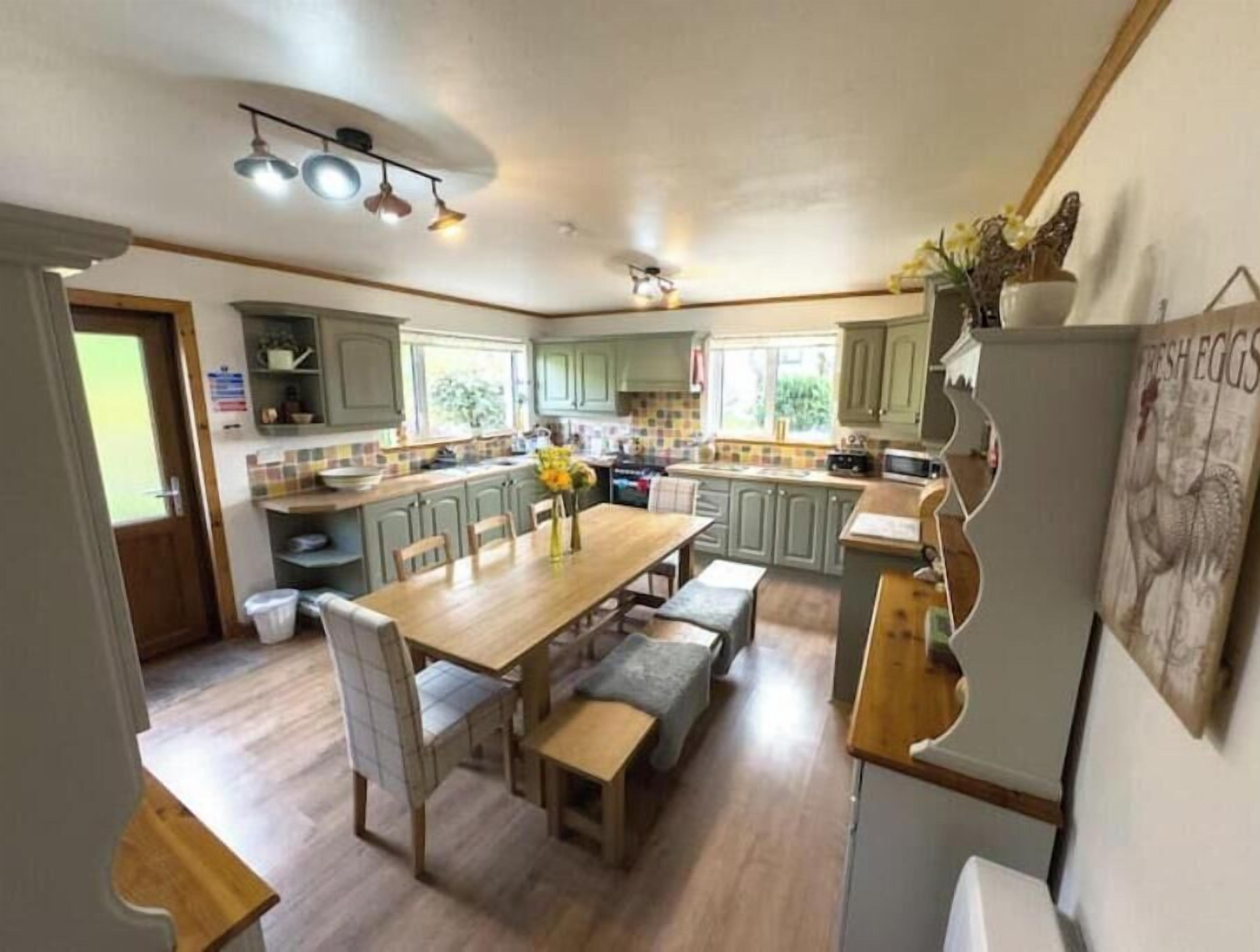 A kitchen with a dining table, chairs, and a refrigerator.