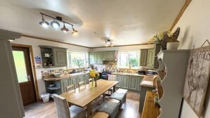 A kitchen with a dining table, chairs, and a refrigerator. - Spacious Family Retreat with Stunning Loch Views near Portree (Portree)