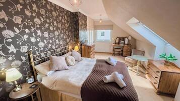A bedroom with a bed, bedside table, lamp, and a dresser.