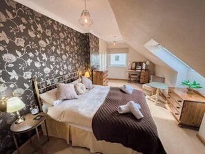 Un dormitorio con cama, mesita de noche, lámpara y cómoda.