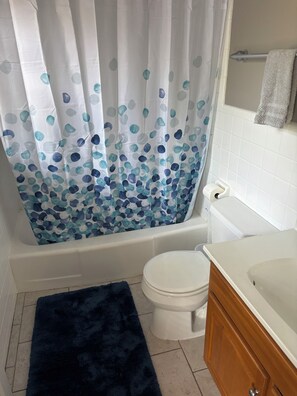 A bathroom with a bathtub, toilet, and wooden vanity. - Stunning lake property with a pool (Hot Springs)