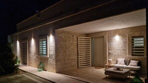 A modern house with a patio, stone walls, and a door with shutters.