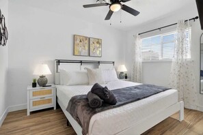 A bedroom with a bed, two bedside tables, a ceiling fan, and artwork on the wall. - 7BR Newly Remodeled Home w/ Arcades, Sleeps 20 (North Las Vegas)