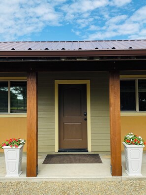A building with a brown door, two white flower planters, and a metal roof. - Rawhide Getaway - Detached Guesthouse (Prescott)
