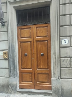 A double wooden door with a metal handle, a window above it, and a building number '5' on the right. - Nest by the Medici Chapels - Attico (Firenze)