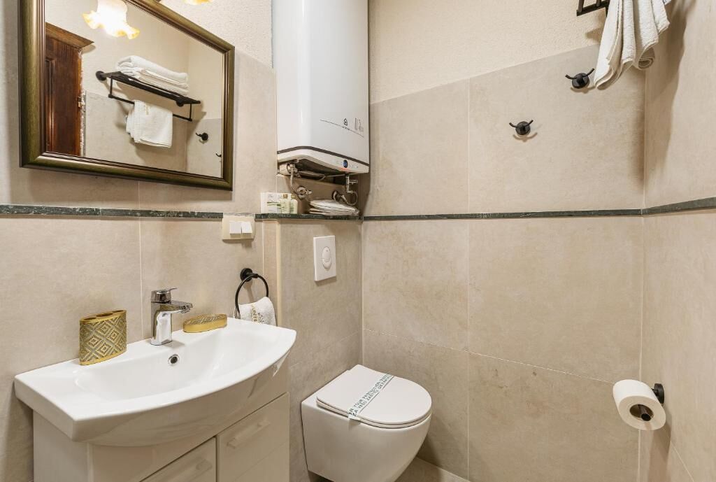 Un baño con lavamanos, inodoro, toallero y espejo.