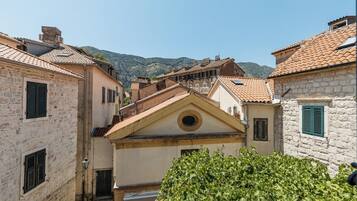 Una calle estrecha con edificios de piedra, una iglesia con campanario y una montaña al fondo.