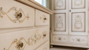 Une commode blanche aux poignées décoratives et un meuble avec des portes miroir et des panneaux décoratifs.