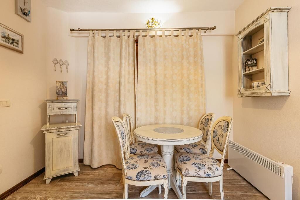 Un comedor con una mesa redonda y cuatro sillas, un mueble bajo y un radiador.