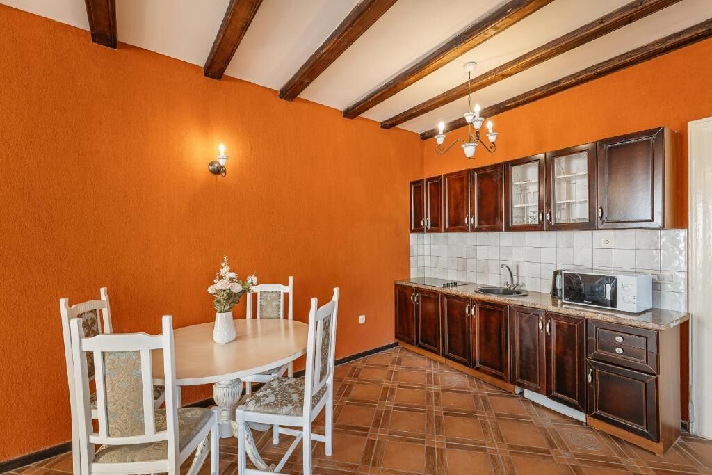 Una cocina con armarios de madera, salpicadero de azulejos, una mesa de comedor con sillas y una lámpara de araña.