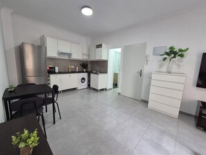 Eine moderne Küche mit Essbereich, einer Waschmaschine und einem an der Wand montierten Fernseher.