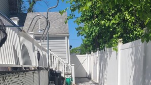 Un chemin pavé bordé de clôtures blanches mène à un bâtiment doté d’une entrée abritée.