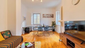 A modern living room with a sofa, a dining table with chairs, a TV, and a chandelier. - Casa Amarela de Sintra for family holidays at the historical Sintra. (Lisboa)