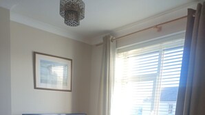 Una sala de estar con televisor, sofá, mesa de centro y ventana con persianas.