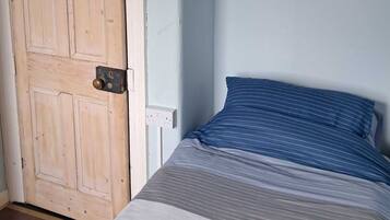 A bedroom with a bed, a wooden door, and a wall with a sign listing Paris landmarks.