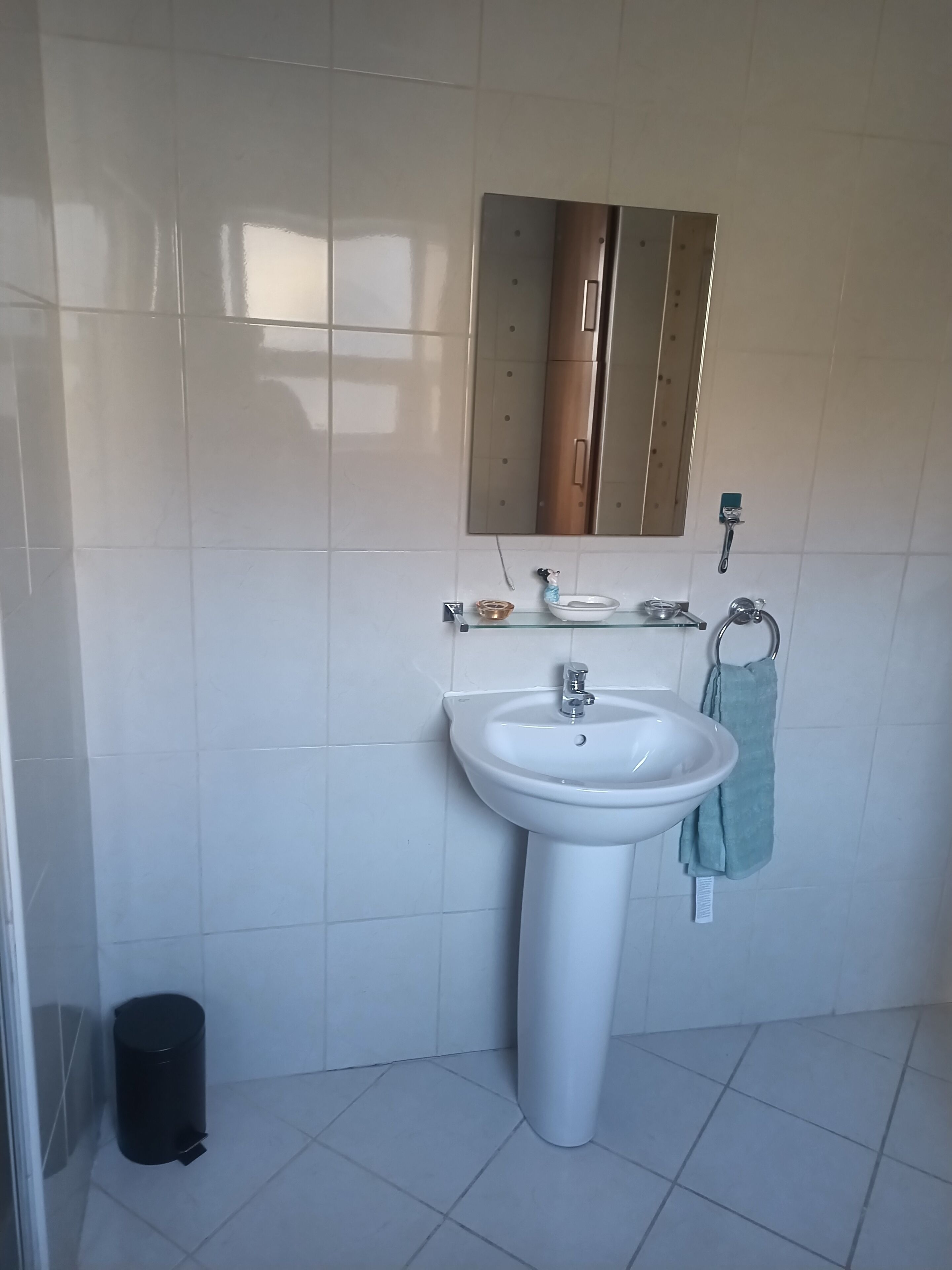 Un bagno con un lavandino bianco, uno specchio e un portasciugamani.