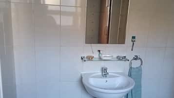 Un bagno con un lavandino bianco, uno specchio e un portasciugamani.