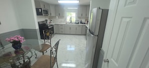 A kitchen with white cabinets, a stainless steel refrigerator, a microwave, and a stove.