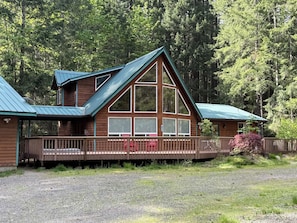 Une cabane avec une façade en bois, de grandes fenêtres et une véranda couverte.