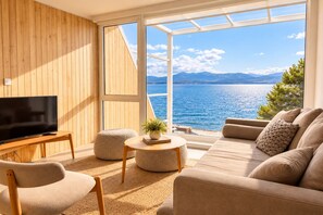 A modern living room with a television, seating, and a view of the sea. - Signature Lake View Luxury Residences Unite Ñ36 (San Carlos de Bariloche)