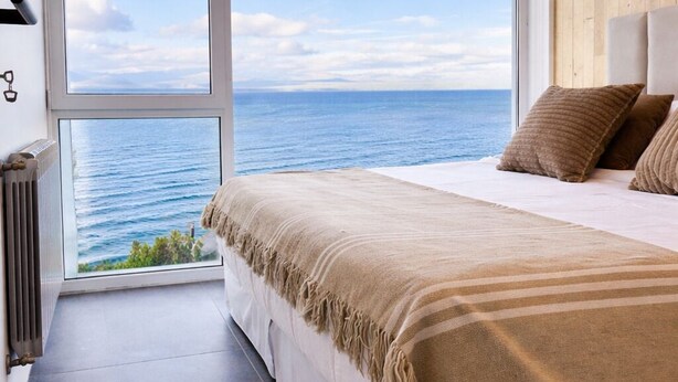 Un dormitorio con una ventana grande, una cama y vistas al mar.