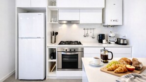 Cocina compacta equipada con refrigerador, estufa, horno y cafetera.