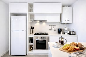 A compact kitchen with a refrigerator, stove, oven, and coffee maker. - Signature Lake View Luxury Residences Unite Ñ36 (San Carlos de Bariloche)